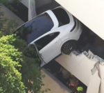 Female saved as crash leaves Porsche dangling from parking garage