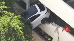 Female saved as crash leaves Porsche dangling from parking garage